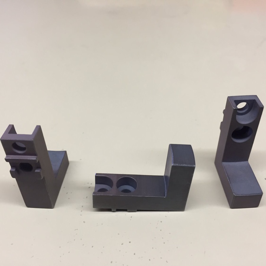 Three machined angle brackets with bored and counterbored holes