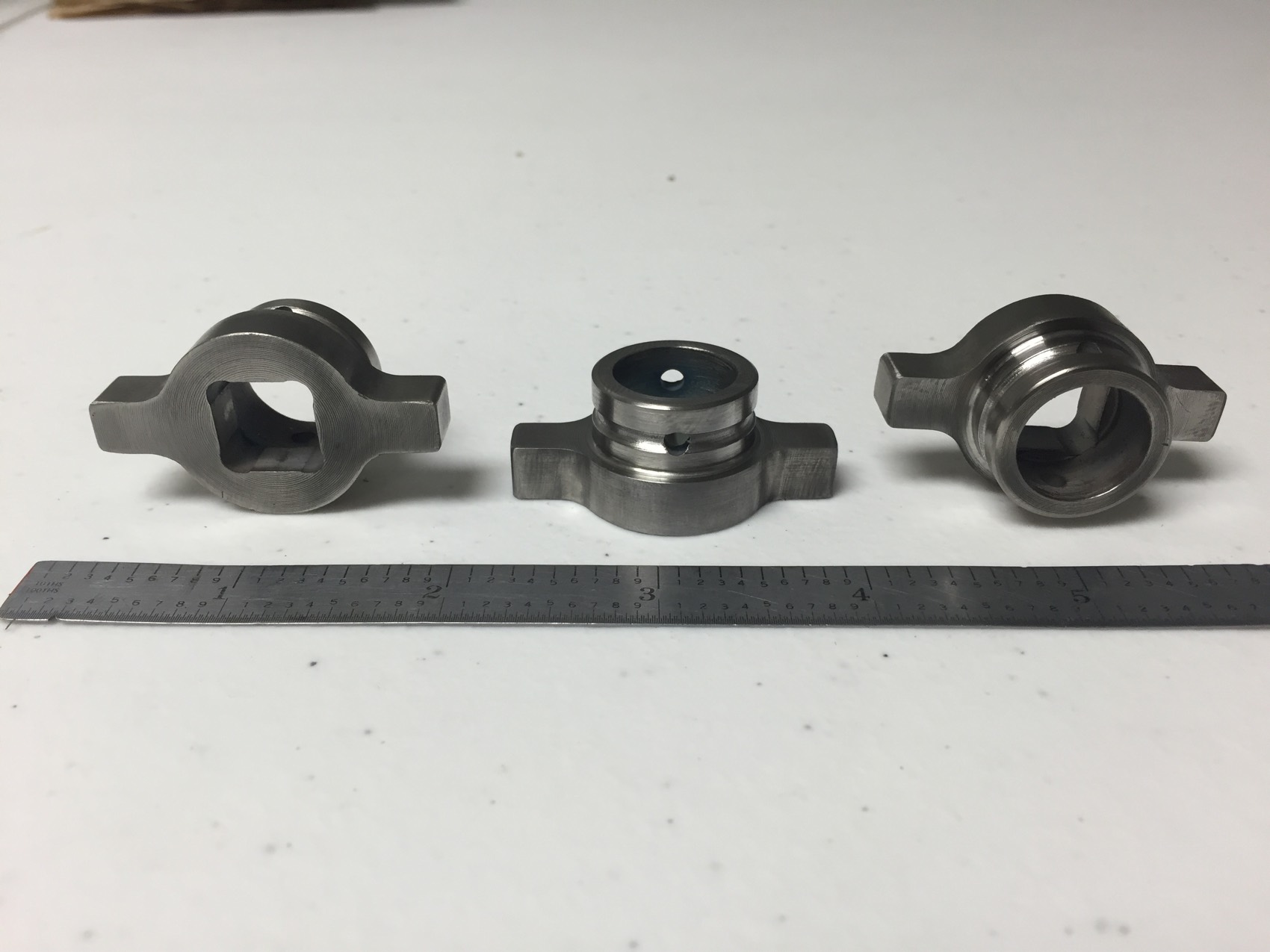 Three matched machined steel yokes beside a steel rule on the inspection table