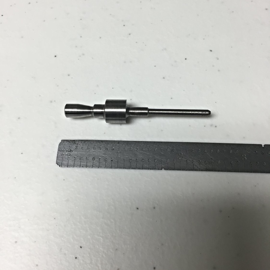 Small precision turned steel pin shown against a steel rule